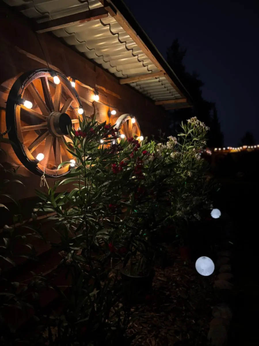 Koło od wozu z lampkami na drewnianej ścianie nocą