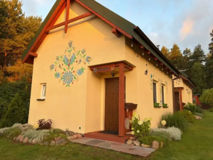 Szczyt domku z kaszubskim wzorem w złotym świetle wschodu, nad nim różowe chmury