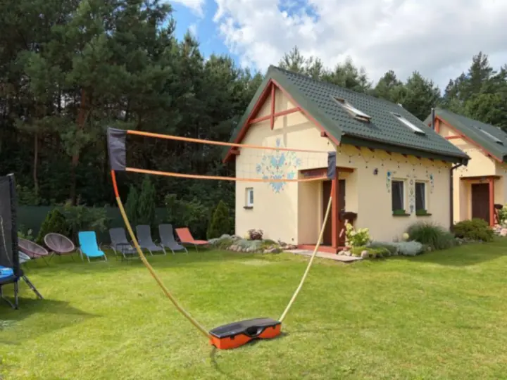 Siatka do siatkówki na trawniku przed domkiem, obok leżaki